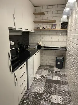 a kitchen with white cabinets and a tiled floor at City Apartmani Niš in Niš
