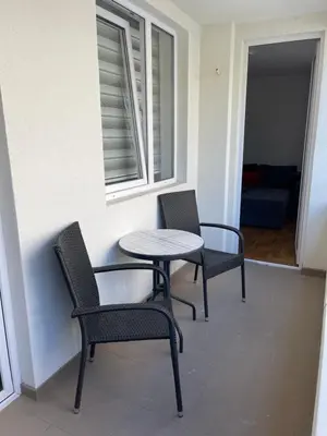 two chairs and a table in a room with a window at City Apartmani Niš in Niš