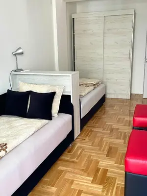 a room with two beds and a red chair at City Apartmani Niš in Niš