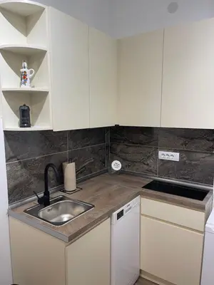 a kitchen with white cabinets and a sink at Enjoyment Apartment in Niš