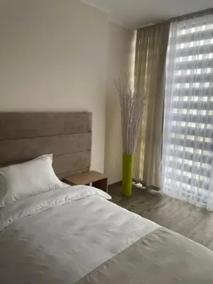 a bedroom with a white bed and a window at Apartmani Joja in Kuršumlija