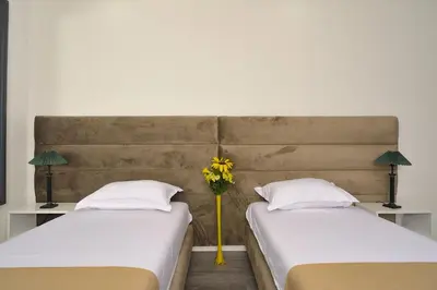 two beds with a vase of yellow flowers between them at Apartmani Joja in Kuršumlija