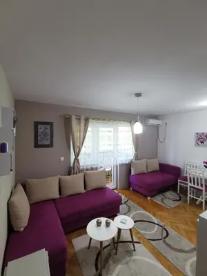 a living room with a purple couch and a table at My bouquet in Vrnjačka Banja