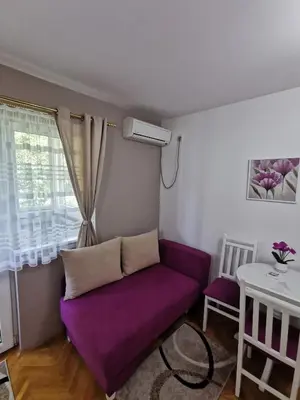 a living room with a purple couch and a table at My bouquet in Vrnjačka Banja