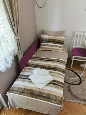 two beds in a small room with a chair at My bouquet in Vrnjačka Banja