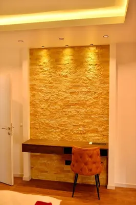 a room with a stone wall and a chair at Bella Superior Apartment in Kruševac