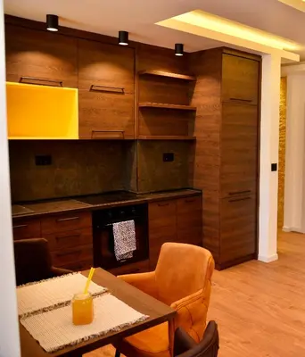 a kitchen with wooden cabinets and a table and chairs at Bella Superior Apartment in Kruševac
