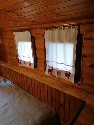 two windows in a log cabin with reindeer curtains at VILA 51 KOPAONIK CENTAR in Kopaonik