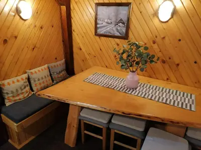 a room with a wooden table with chairs and a vase of flowers at VILA 51 KOPAONIK CENTAR in Kopaonik