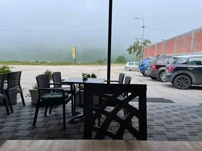 a table and chairs on a patio with a parking lot at Prenociste 