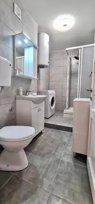 a bathroom with a toilet sink and a washing machine at Apartman Leon Lux in Leskovac
