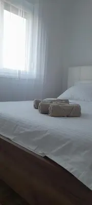 two towels on a bed in a room with a window at Apartmani Sunlight in Vrnjačka Banja