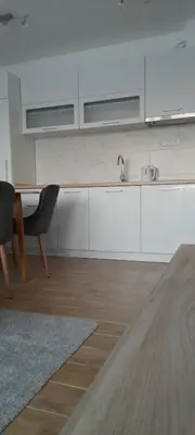 a kitchen with white cabinets and a sink and a table at Apartmani Sunlight in Vrnjačka Banja