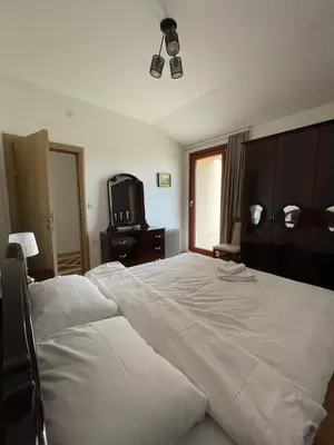 a bedroom with a large white bed and a tv at Apartman AS in Vrnjačka Banja