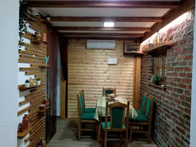 a dining room with a table and green chairs at Apartman Konak in Zaječar