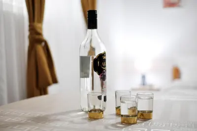 a bottle of wine and three glasses on a table at Stil Park Apartmani in Vrnjačka Banja