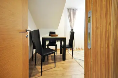 a dining room table with black chairs and a laptop on it at Stil Park Apartmani in Vrnjačka Banja