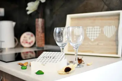 two wine glasses on a counter with a love sign at Stil Park Apartmani in Vrnjačka Banja