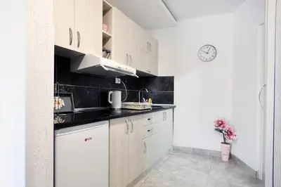 a kitchen with white cabinets and a clock on the wall at Stil Park Apartmani in Vrnjačka Banja