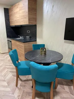 a dining room with a table and blue chairs at Pink House Apartments in Jagodina