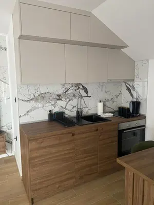 a kitchen with white cabinets and a counter top at Apartmani Lazarevic Jagodina in Jagodina