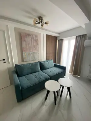 a living room with a blue couch and two tables at Apartmani Lazarevic Jagodina in Jagodina