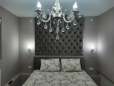 a bedroom with a bed with a headboard and a chandelier at Apartment Sweet dreams 4 in Niš