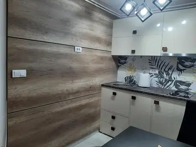 a kitchen with white cabinets and a wooden wall at Apartment Sweet dreams 4 in Niš