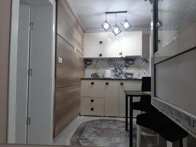 a kitchen with white cabinets and a table and a tv at Apartment Sweet dreams 4 in Niš