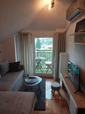 a living room with a couch and a television and a balcony at Promenada View Snežnik in Vrnjačka Banja