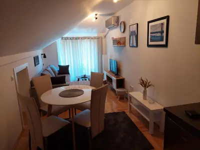 a living room with a table and a dining room at Promenada View Snežnik in Vrnjačka Banja