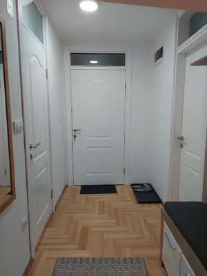 a hallway with a white door and a wooden floor at Promenada View Snežnik in Vrnjačka Banja