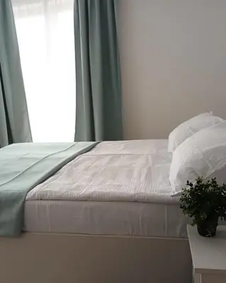 a bed with white sheets and pillows next to a window at Milutinn-Visterija in Soko Banja