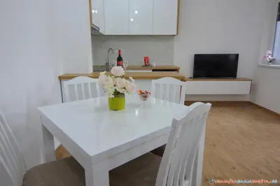 a white dining room table with a vase of flowers on it at Neda Lux Apartmani 5 nocenja, šesto gratis in Vrnjačka Banja
