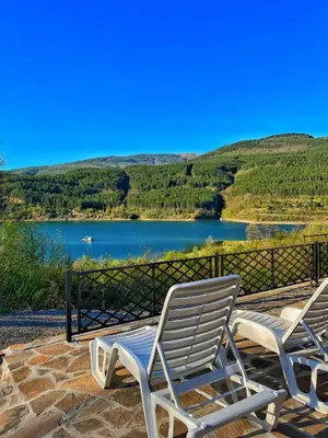 two lounge chairs on a patio with a view of a lake at Zavojsko jezero - Vila Jezero in Pirot