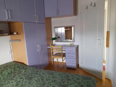 a bedroom with a bed and a desk and a mirror at Family Apartman in Jagodina