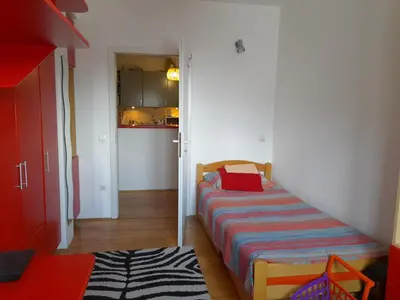 a small bedroom with a bed and a kitchen at Family Apartman in Jagodina