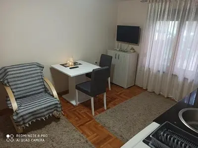 a living room with a desk and a table with a chair at Apartman Mila in Niš