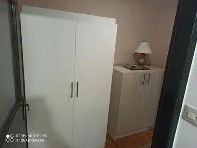 a white cabinet and a lamp in a room at Apartman Mila in Niš