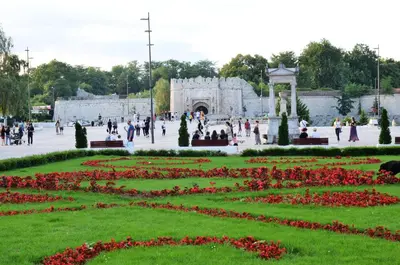 a park with red flowers and people walking around at TIKE, TAK - Central Residence in Niš