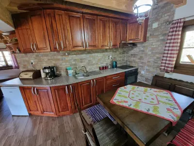 a kitchen with wooden cabinets and a table in it at Country House Sunčev breg in Bara Slatina