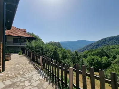 a fence next to a house with mountains in the background at Country House Sunčev breg in Bara Slatina