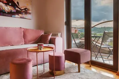 a living room with a couch and two stools and a table at Apartman 'Kapljica' in Vrnjačka Banja