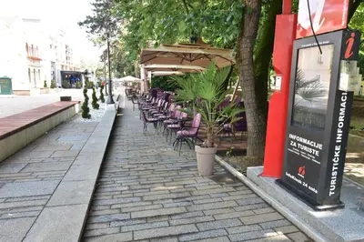 a row of chairs and umbrellas on a sidewalk at Apartman Lipa 11 in Vrnjačka Banja