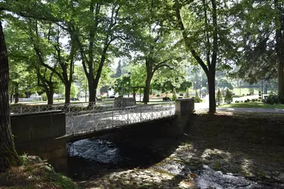 a bridge over a river in a park with trees at Apartman Lipa 11 in Vrnjačka Banja