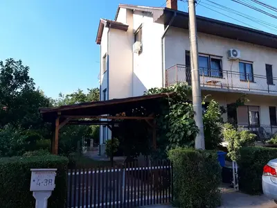 a white building with a wooden canopy in front of it at Apartman Ljiljan in Niš