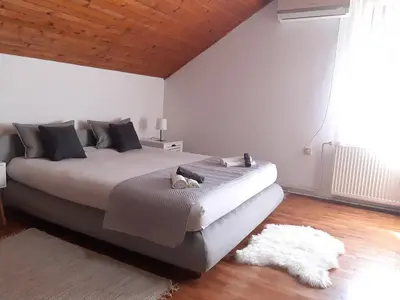 a bedroom with a large bed and a rug at Apartman Ljiljan in Niš