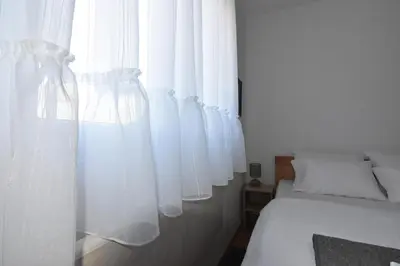 a bedroom with white curtains on the window at Apartman Point in Vrnjačka Banja