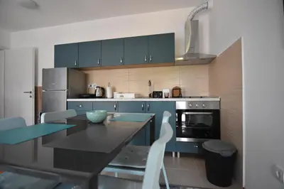 a kitchen with blue cabinets and a black table and chairs at Apartman Point in Vrnjačka Banja