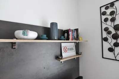 a shelf on a wall with a clock and books at Apartman Point in Vrnjačka Banja